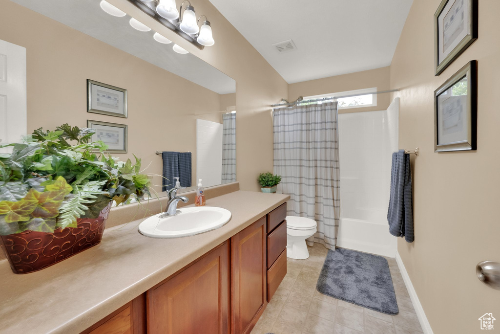 Full bath with vanity, shower / bath combo with shower curtain, and tile patterned floors