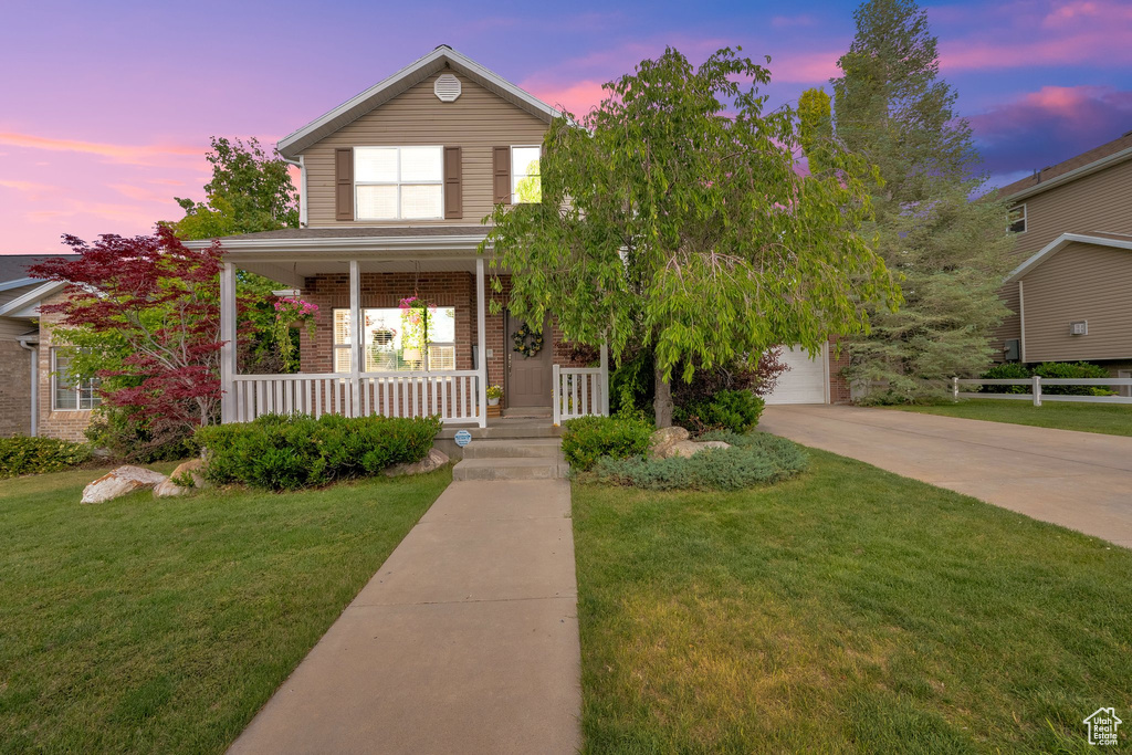 Traditional-style home with covered porch, concrete driveway, brick siding, and a garage