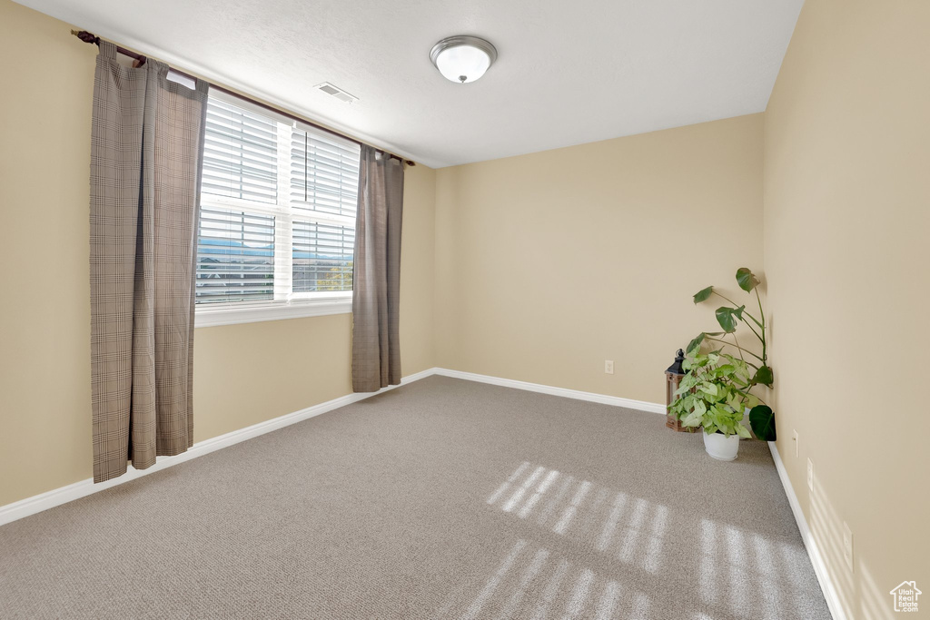 Spare room featuring carpet and baseboards
