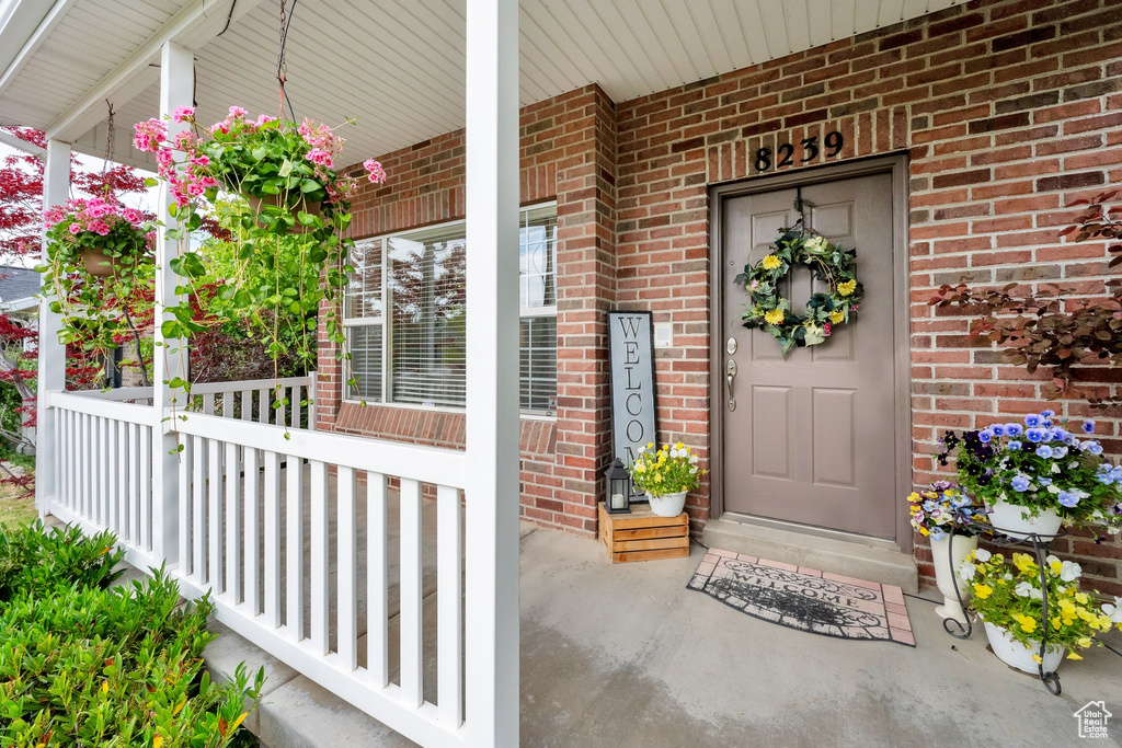 Entrance to property with covered porch and brick siding
