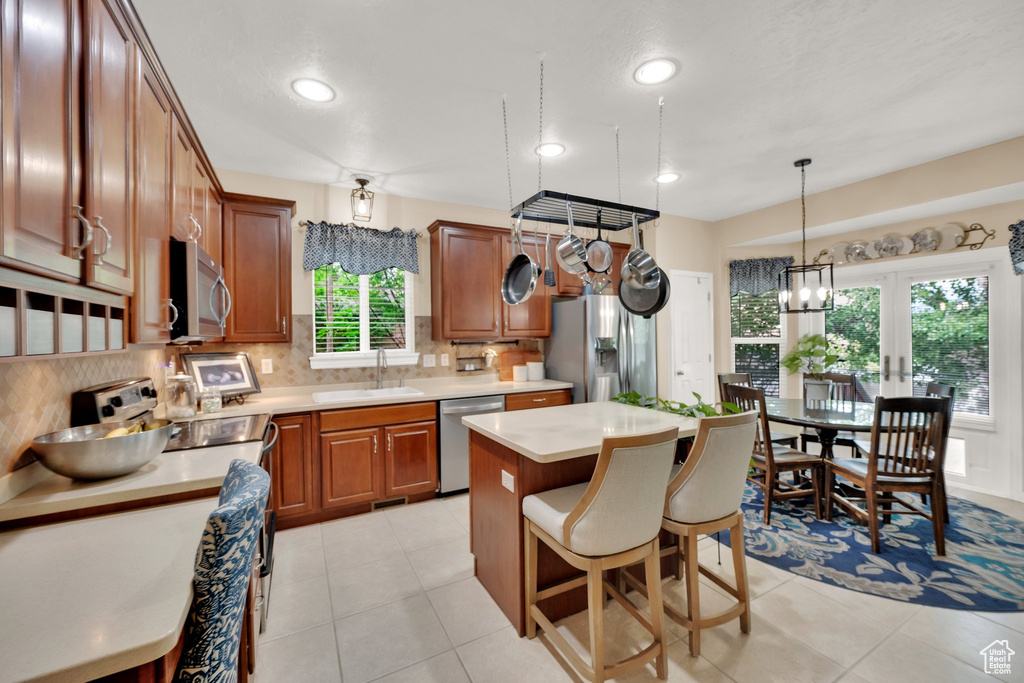Kitchen featuring appliances with stainless steel finishes, brown cabinetry, backsplash, light countertops, and recessed lighting