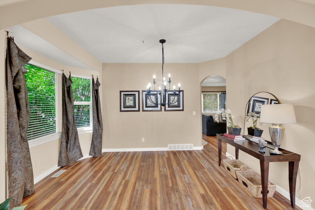 Dining area featuring wood finished floors, arched walkways, and a chandelier