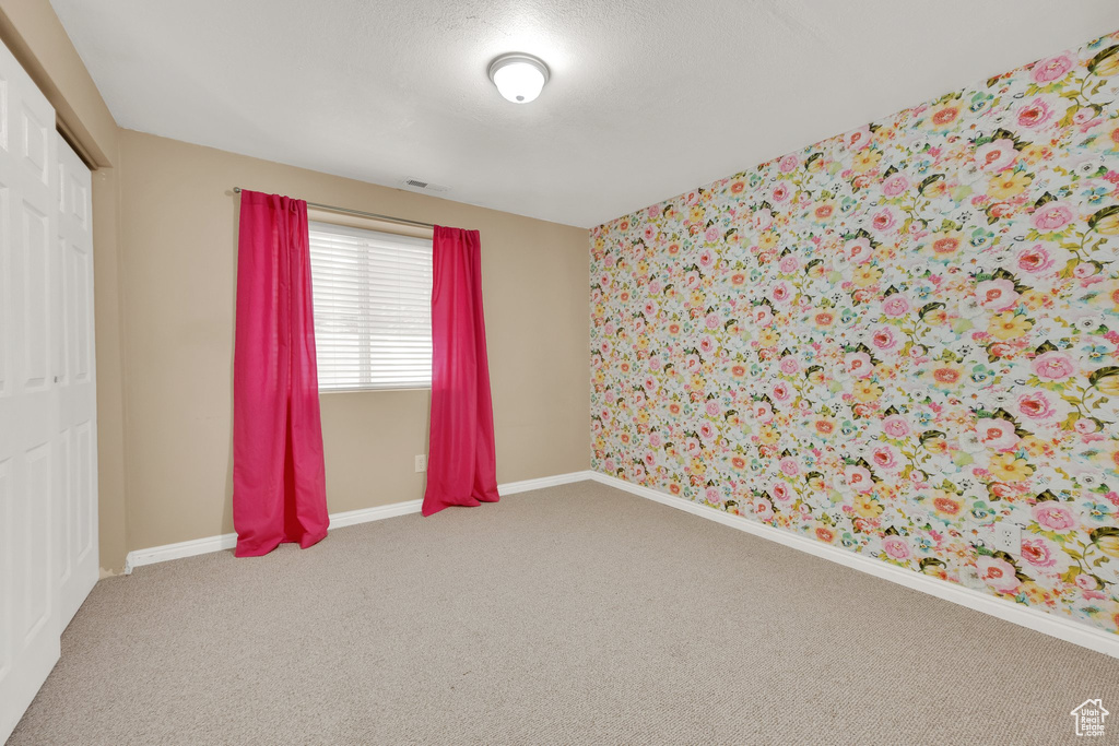 Unfurnished room featuring wallpapered walls and carpet