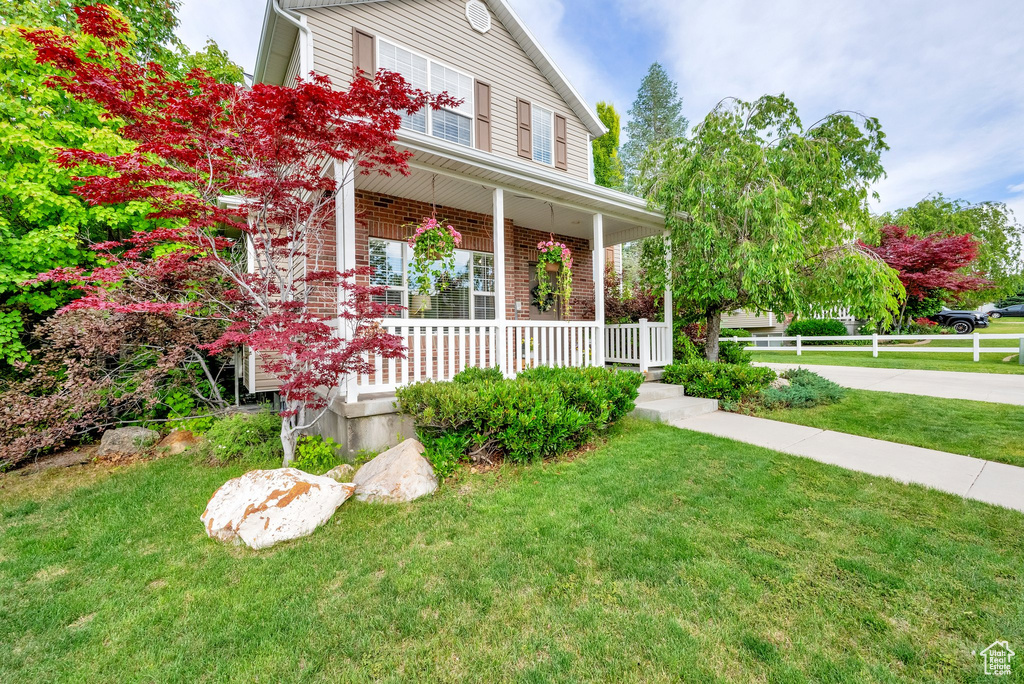 View of front of property with a porch, a front yard, and brick siding