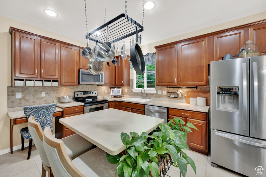 Kitchen with stainless steel appliances, light tile patterned floors, backsplash, light countertops, and recessed lighting