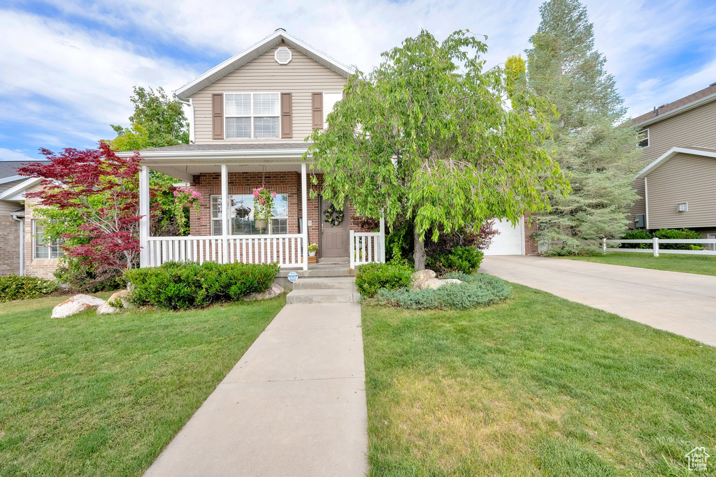 Traditional-style house with a porch, driveway, brick siding, and a garage