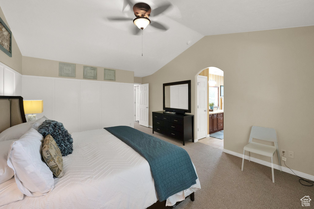 Bedroom featuring arched walkways, lofted ceiling, carpet, ceiling fan, and ensuite bath