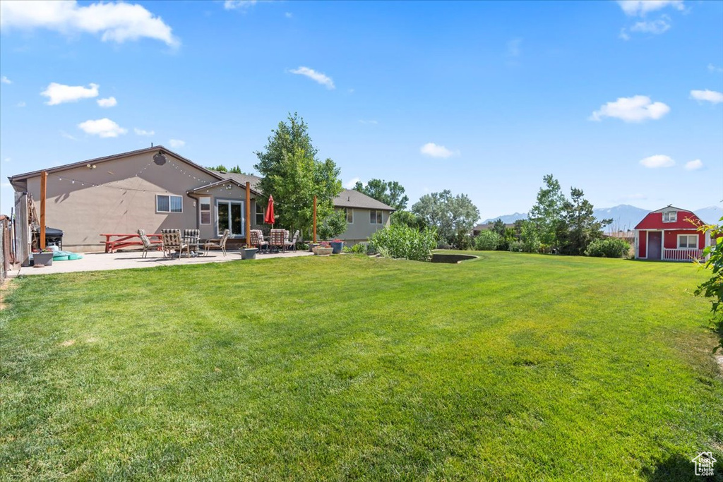 View of green lawn featuring a patio and a mountain view
