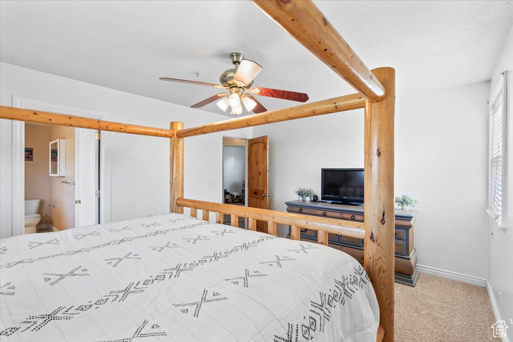 Bedroom with carpet floors, ensuite bathroom, and ceiling fan