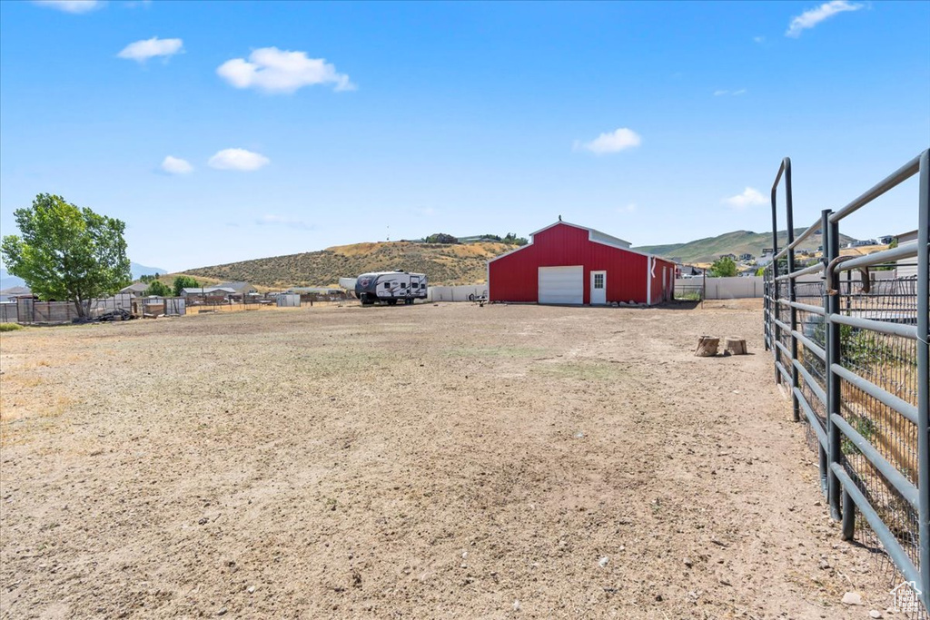View of yard featuring a detached garage, an outbuilding, a mountain view, and dirt driveway