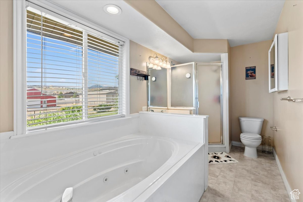 Bathroom with a stall shower, a jetted tub, and plenty of natural light