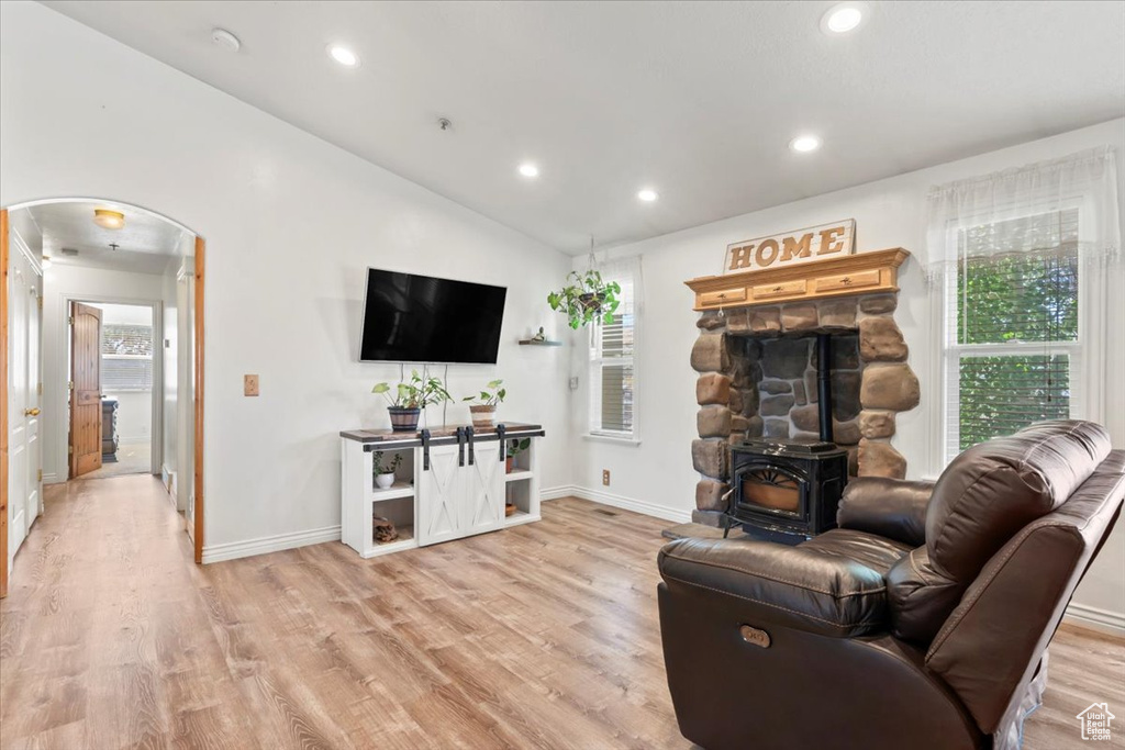 Living area featuring arched walkways, light wood-style floors, recessed lighting, a wood stove, and vaulted ceiling