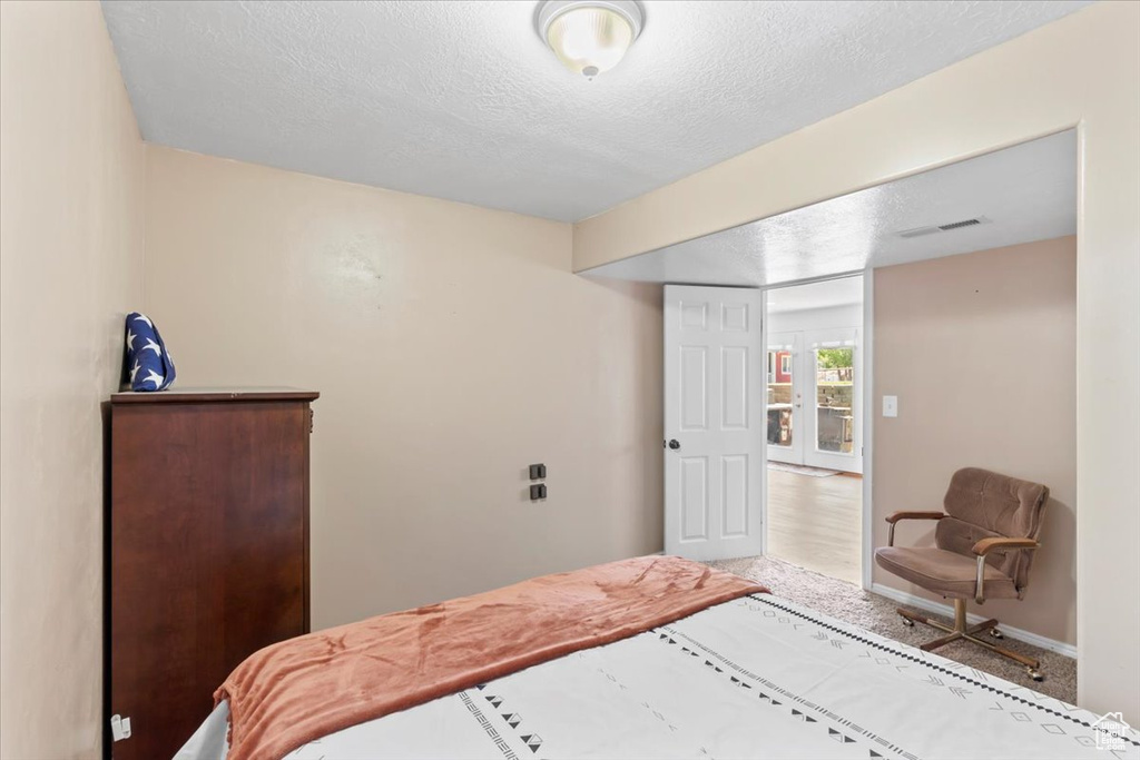 Carpeted bedroom with a textured ceiling and baseboards