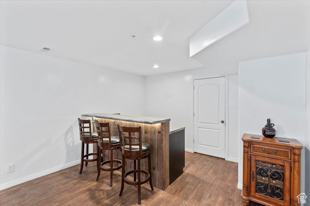Indoor dry bar with dark wood finished floors and recessed lighting