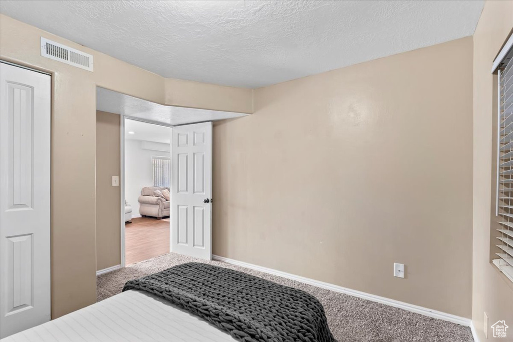 Carpeted bedroom featuring baseboards and a textured ceiling