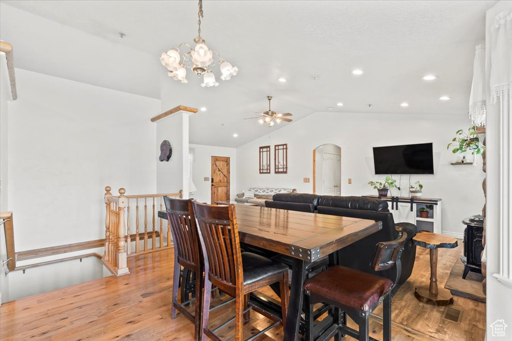 Dining area featuring light wood-style flooring, vaulted ceiling, recessed lighting, arched walkways, and ceiling fan