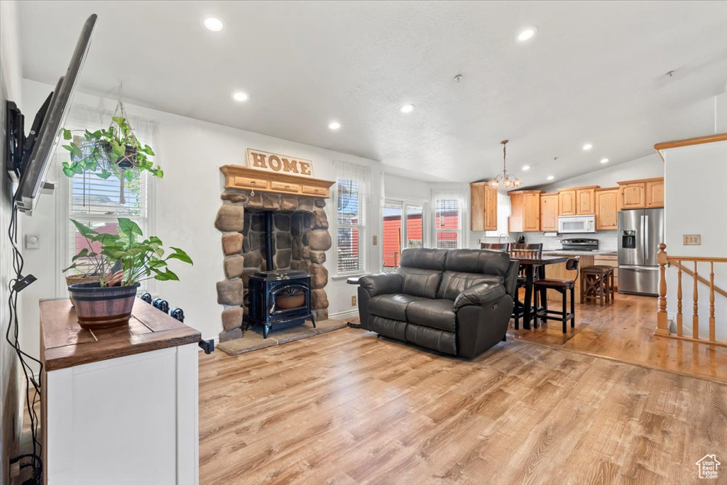 Living area with light wood-type flooring, healthy amount of natural light, a wood stove, lofted ceiling, and recessed lighting