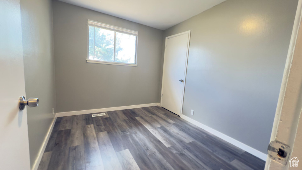 Unfurnished room with baseboards and dark wood-style floors