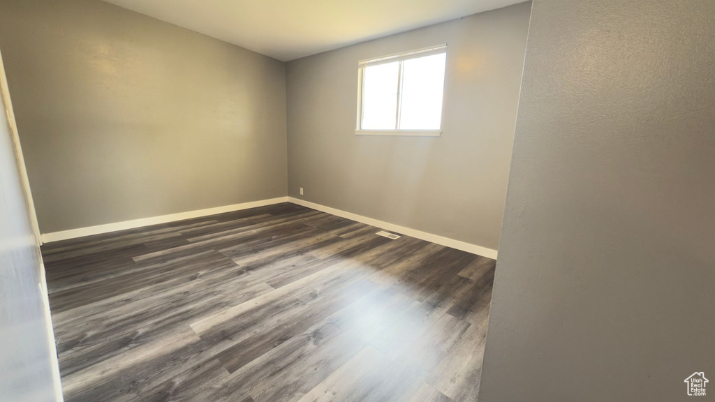 Unfurnished room with baseboards and dark wood-style floors