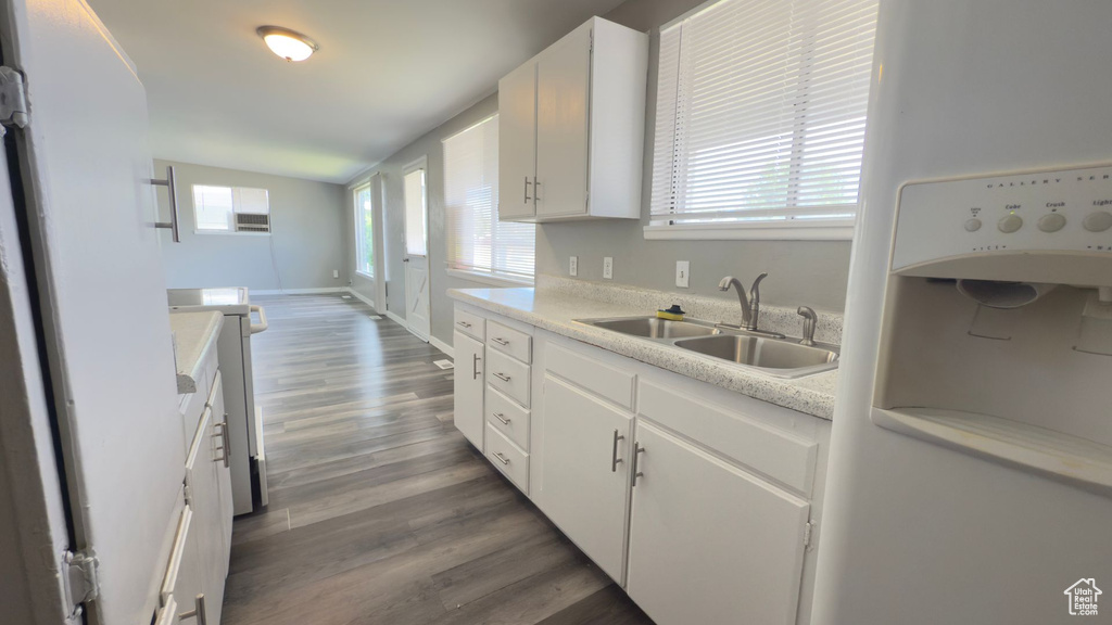 Kitchen featuring white fridge with ice dispenser, range, wood finished floors, and plenty of natural light