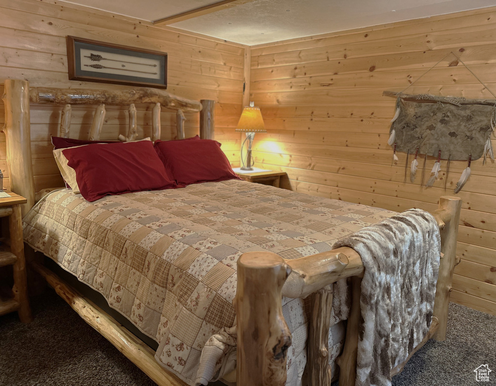 Carpeted bedroom featuring wooden walls