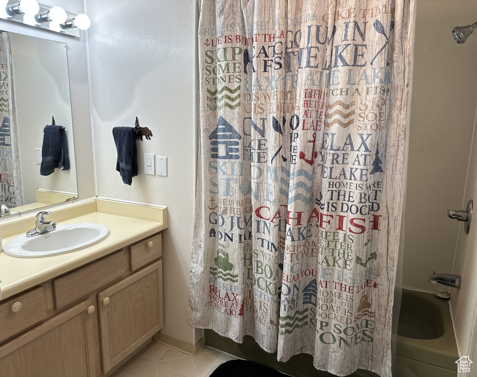 Bathroom featuring vanity, shower / bathtub combination with curtain, and tile patterned flooring