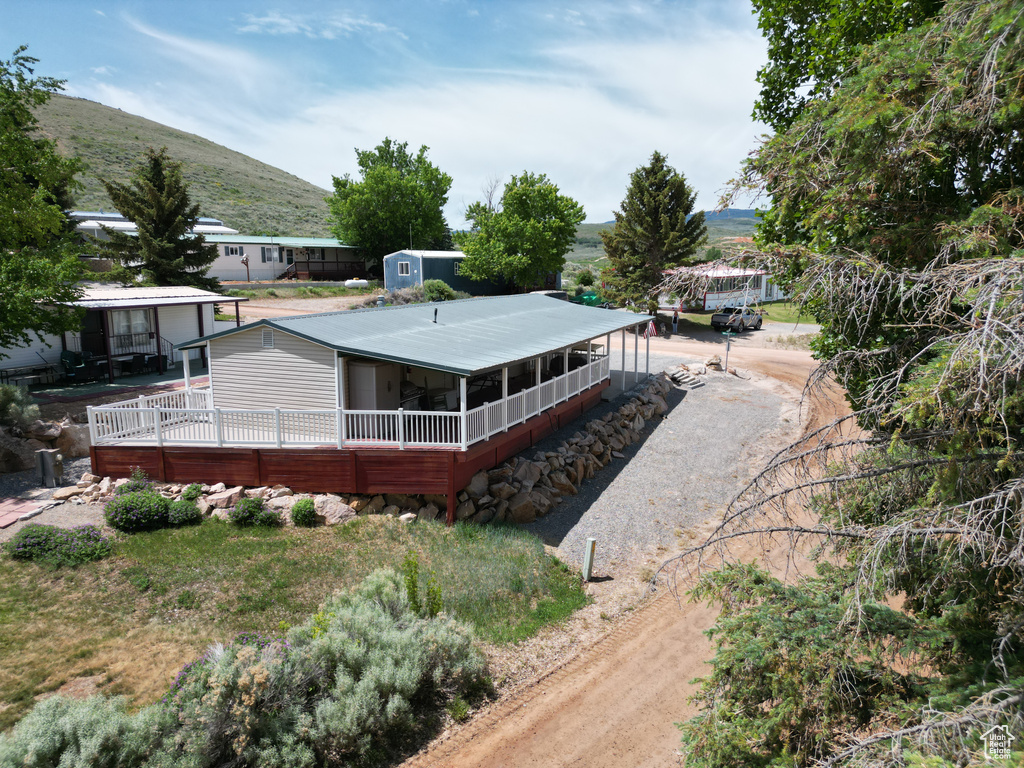 Back of property featuring a sunroom, a mountain view, and dirt driveway