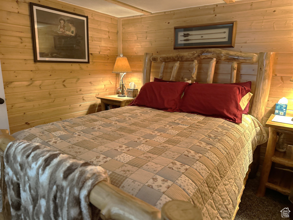 Carpeted bedroom featuring wood walls