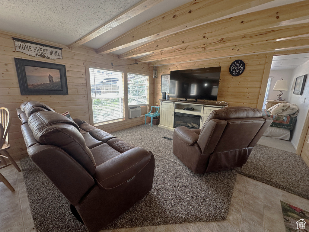 Living area featuring wooden walls, beam ceiling, cooling unit, a glass covered fireplace, and a textured ceiling