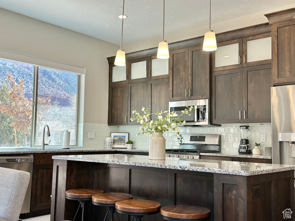 Kitchen with stainless steel appliances, dark brown cabinets, and tasteful backsplash