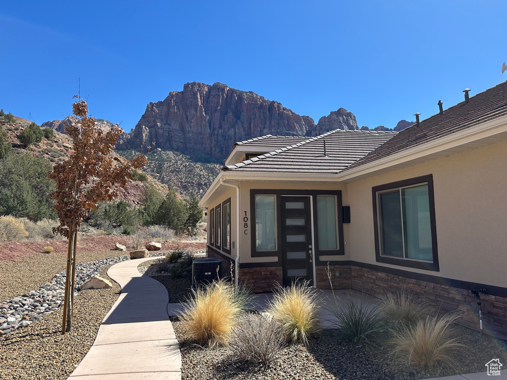 View of side of home featuring a mountain view, stone siding, stucco siding, and a tiled roof