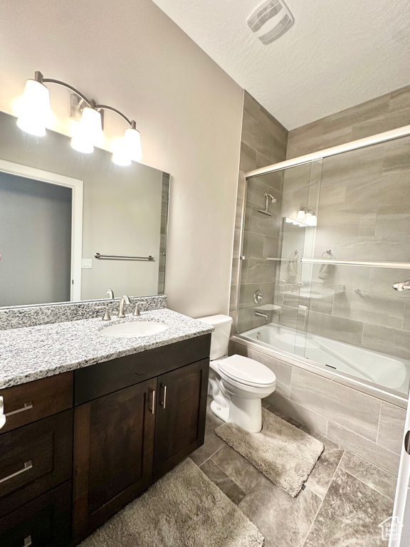 Bathroom featuring shower / bath combination with glass door, vanity, and tile patterned floors