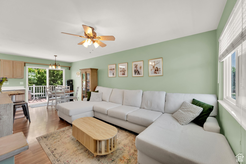 Living room with light wood finished floors, ceiling fan, and a chandelier