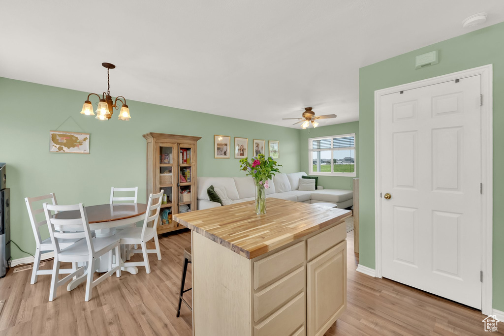 Kitchen featuring wooden counters, light wood finished floors, a ceiling fan, pendant lighting, and a breakfast bar area
