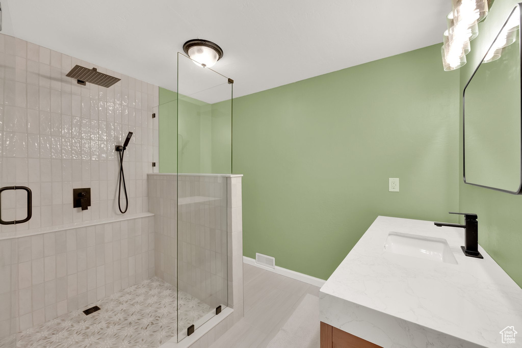 Bathroom with vanity, tiled shower, and wood finished floors