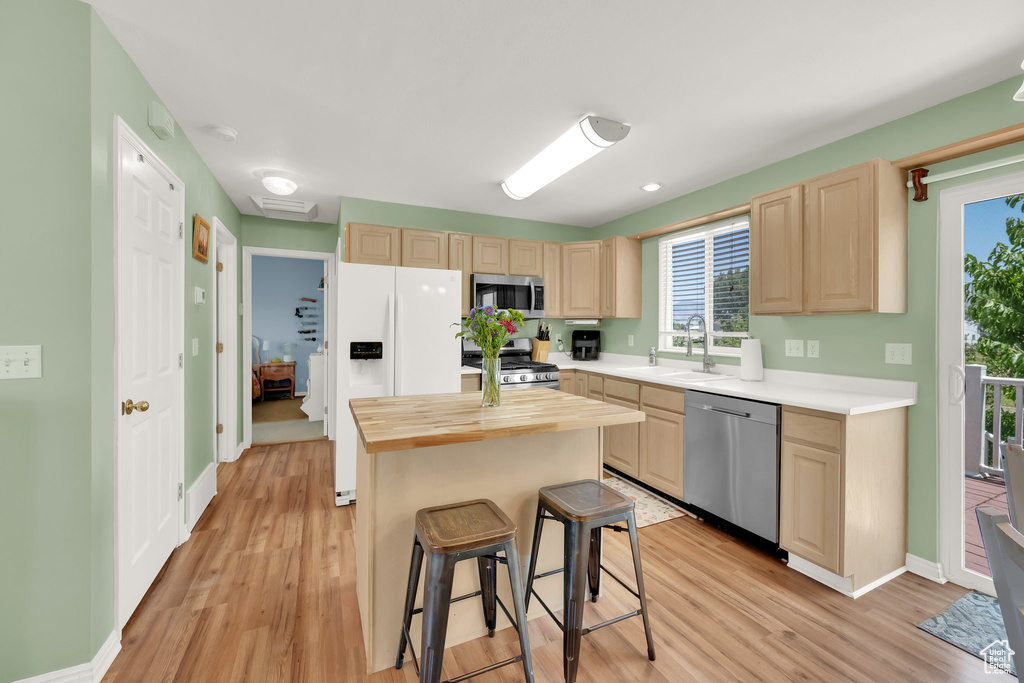 Kitchen featuring stainless steel appliances, light brown cabinets, butcher block countertops, and light wood-style flooring