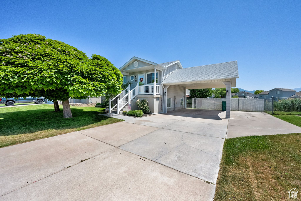 Raised beach house with concrete driveway, a porch, and stairs