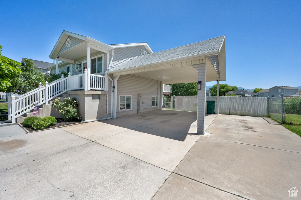 View of front facade featuring concrete driveway, roof with shingles, and an attached carport