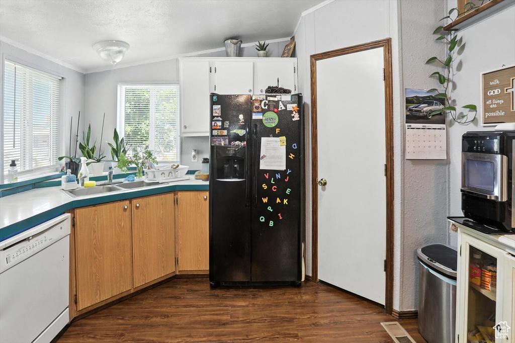 Kitchen featuring black fridge with ice dispenser, dishwasher, dark wood-type flooring, ornamental molding, and light countertops
