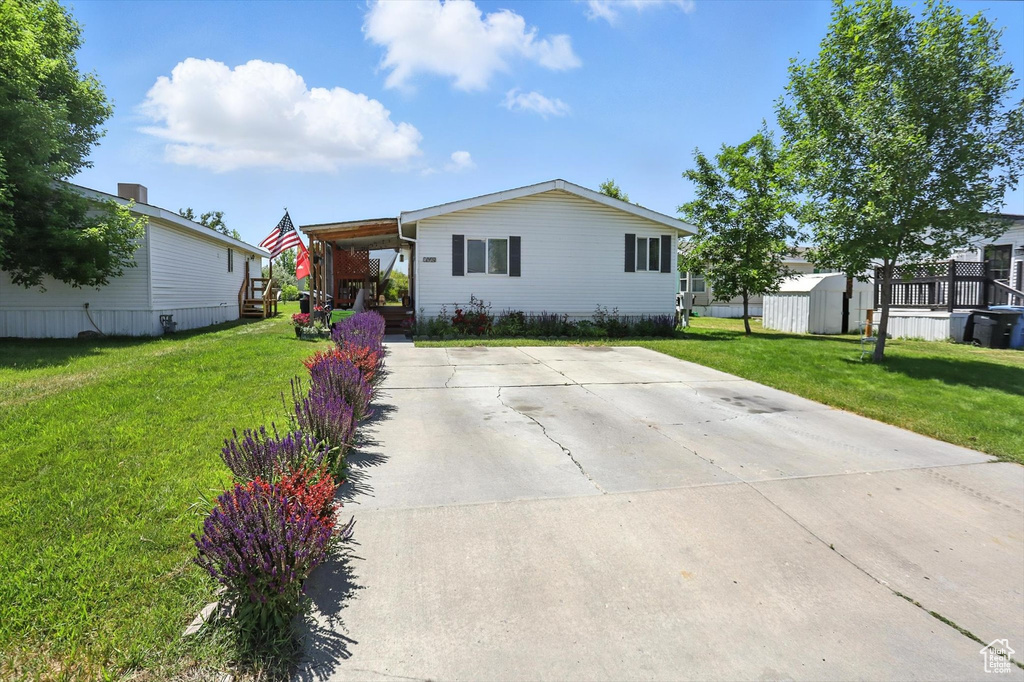 Manufactured / mobile home featuring a storage shed, a front yard, and driveway