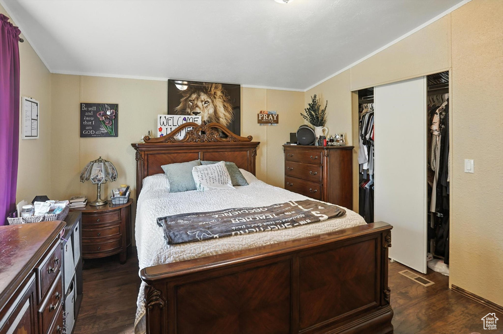 Bedroom featuring dark wood-style flooring, crown molding, and a closet