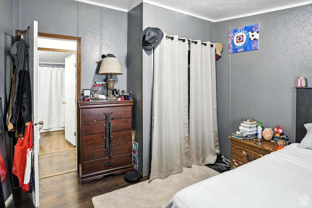 Bedroom with wood finished floors and a textured wall