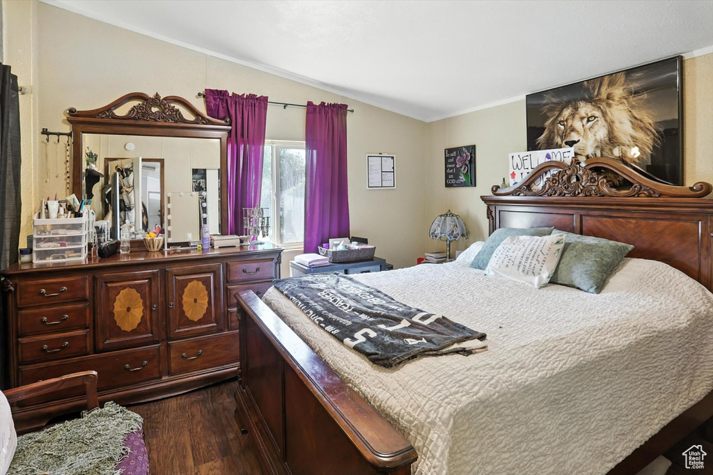 Bedroom featuring lofted ceiling, dark wood-type flooring, and crown molding