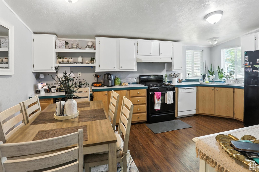 Kitchen featuring black appliances, under cabinet range hood, dark wood-type flooring, a textured ceiling, and light countertops