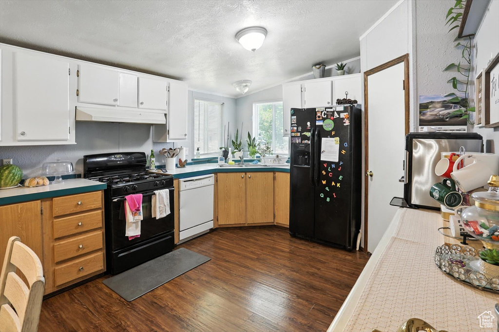 Kitchen featuring black appliances, under cabinet range hood, dark wood finished floors, light countertops, and vaulted ceiling