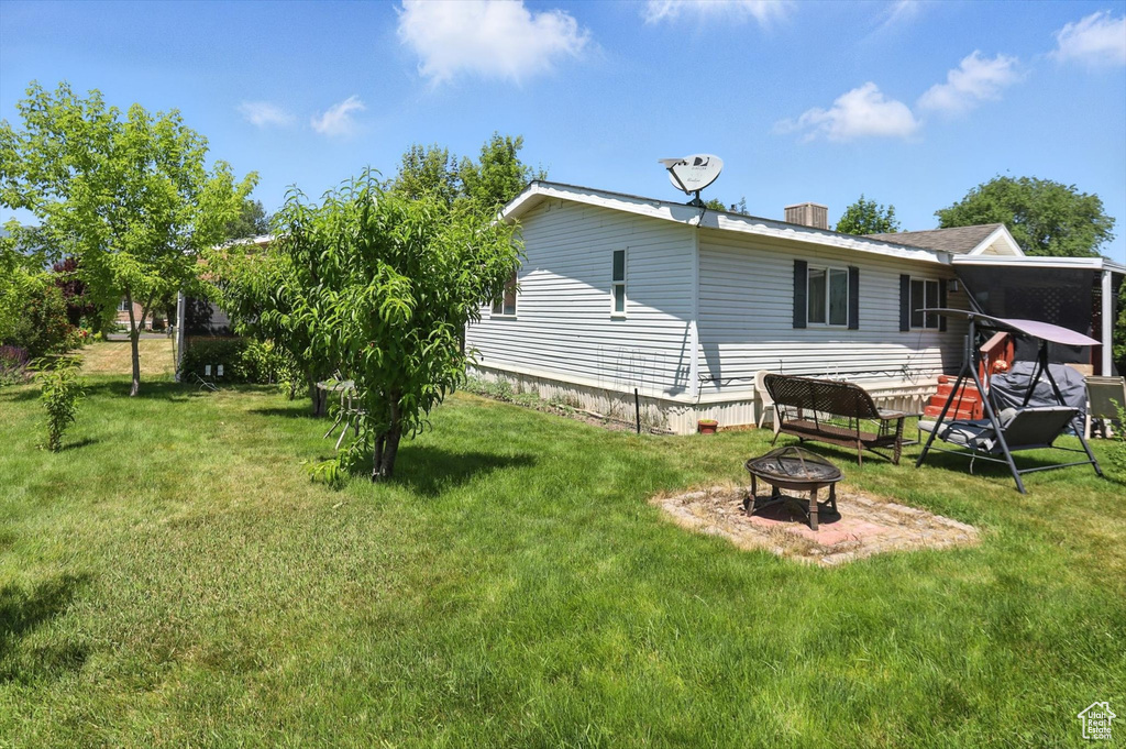 Rear view of property featuring a fire pit and a lawn