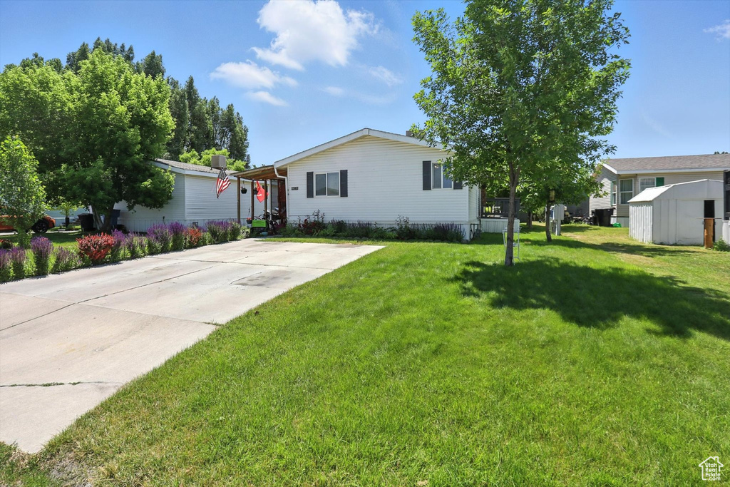 Manufactured / mobile home with a front lawn and a storage unit