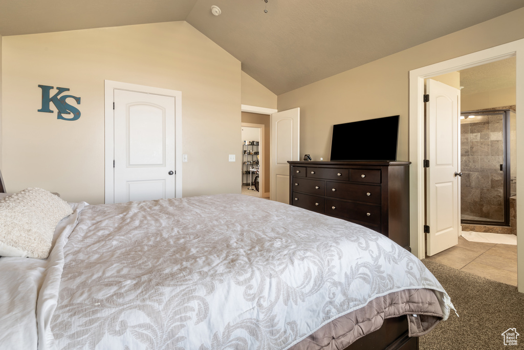 Bedroom with lofted ceiling, ensuite bathroom, tile patterned floors, and carpet