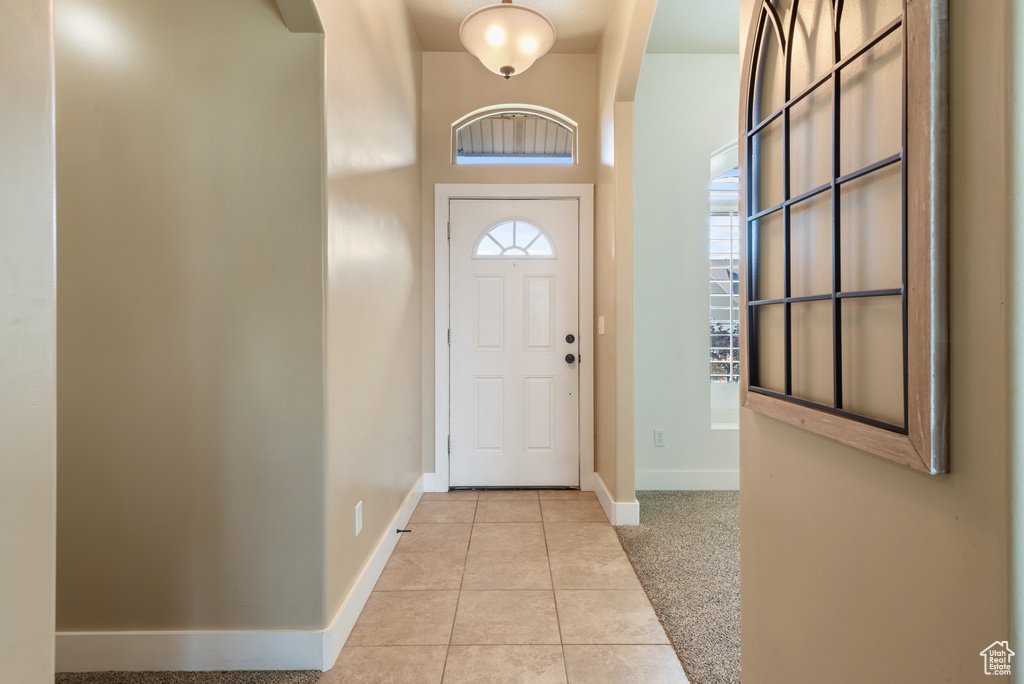 Foyer entrance with light tile patterned floors and baseboards