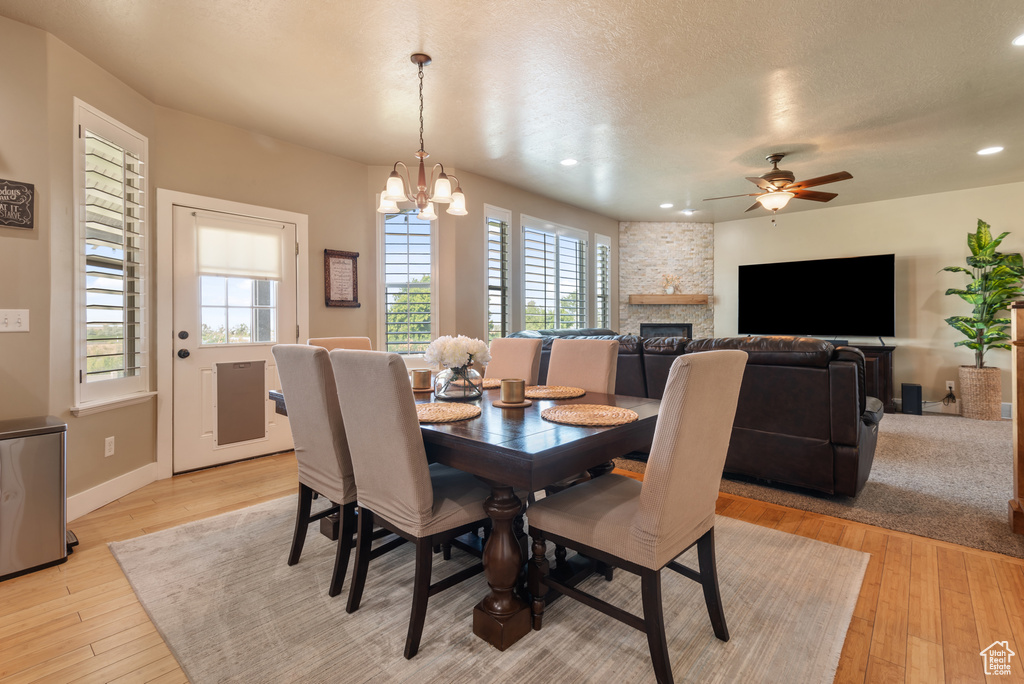 Dining room featuring healthy amount of natural light, light wood finished floors, a fireplace, recessed lighting, and a ceiling fan